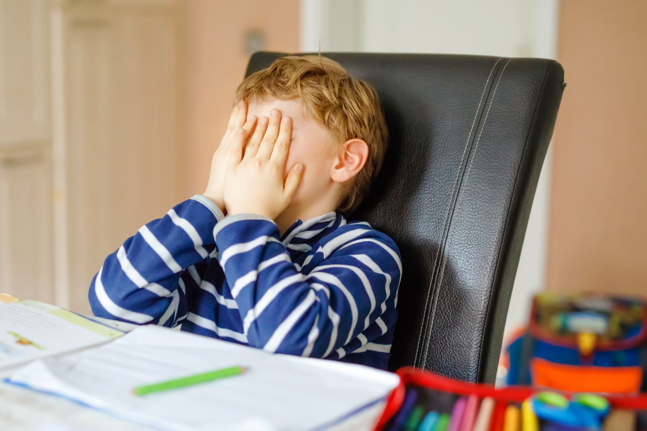 Upset school kid boy making homework during quarantine time from corona