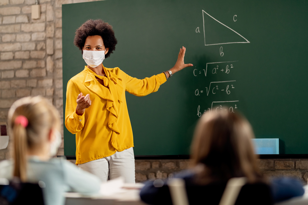 Black teacher wearing face mask while explaining math lesson in the